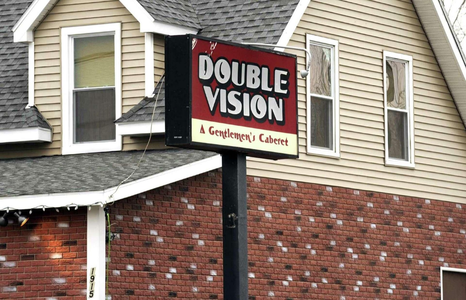 Older Double Vision sign reading A Gentlemen's Cabaret, with the number 1915 on the brick wall