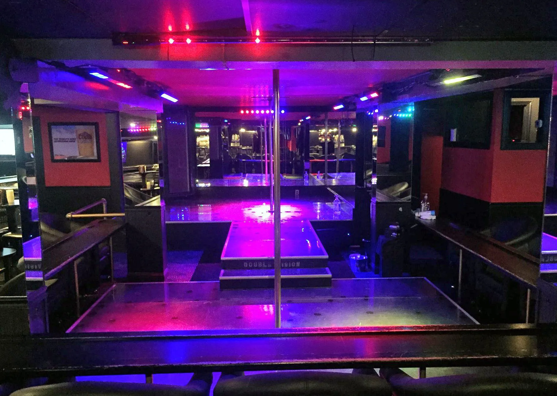 Double Vision main room with a mirrored stage, colored lights, and poles